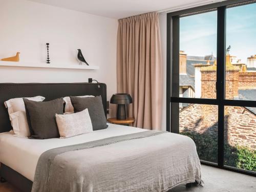a bedroom with a bed and a large window at Balthazar Hotel & Spa Rennes - MGallery Collection in Rennes