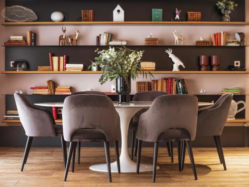 a dining room with a table with chairs and bookshelves at Balthazar Hotel & Spa Rennes - MGallery Collection in Rennes