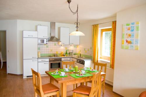 eine Küche mit einem Tisch und Stühlen sowie eine Küche mit weißen Geräten in der Unterkunft Appartmentanlage Isegrim in Altenmarkt im Pongau