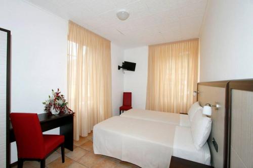 a bedroom with a white bed and a desk and a red chair at Albergo Maccagno in Maccagno Inferiore