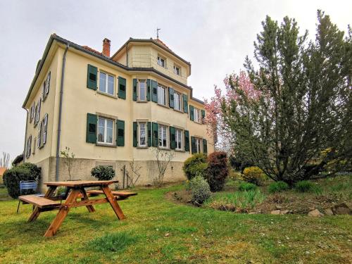 a picnic table in front of a large house at La Tirelire in Cosswiller