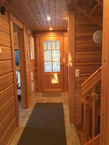 a hallway in a log cabin with a door and a rug at Villa Sea Golf Rönnäs in Loviisa