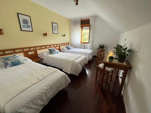 a hotel room with three beds and a table at Hotel Capitán in Cangas de Onís