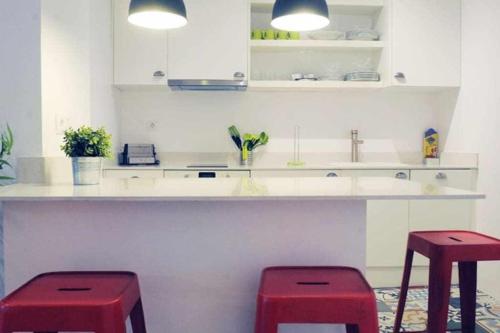 巴塞隆納的住宿－Modern Apartment，厨房在柜台前设有两个红色凳子