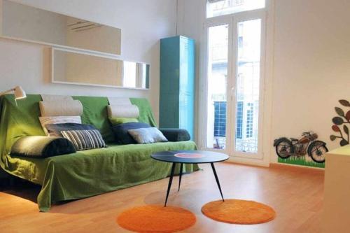 a living room with a green couch and a table at Modern Apartment in Barcelona