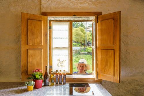 Una mujer mayor mirando por una ventana en Azenha da Lavoura em Barrega, en Celorico de Basto