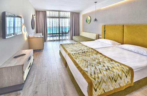a hotel room with a large bed and a couch at GRIFID Encanto Beach Hotel - MediSPA, Ultra All Inclusive & Private Beach in Golden Sands