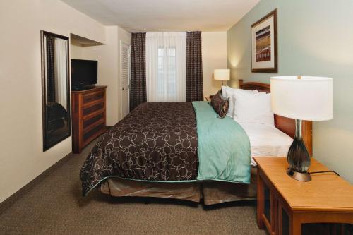 a hotel room with a bed and a lamp and a television at Sonesta ES Suites Dallas - Las Colinas in Irving
