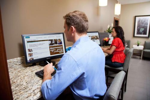 a man sitting at a desk working on a computer at Sonesta ES Suites Dallas - Las Colinas in Irving