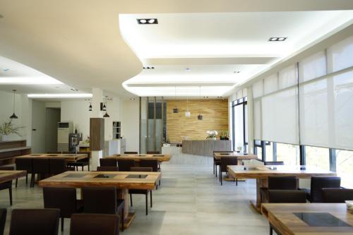 un restaurant avec des tables et des chaises en bois ainsi que des fenêtres dans l'établissement 清境依山舞林民宿, à Renai