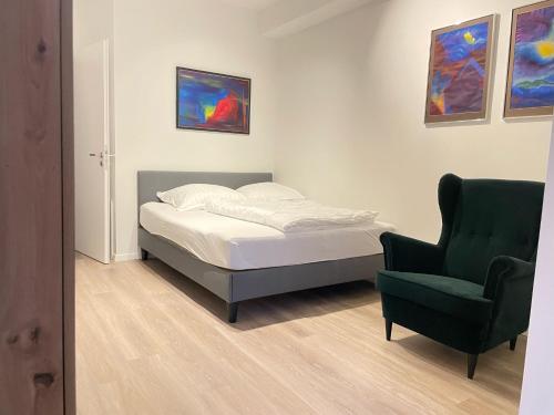 1 dormitorio con 1 cama y 1 silla verde en Office Apartment zentral zur Dortmunder Innenstadt, en Dortmund