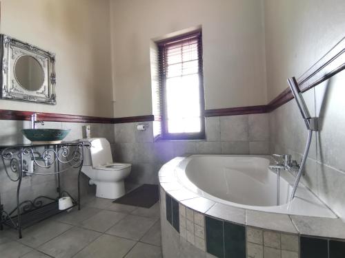a bathroom with a tub and a toilet and a sink at Kralinbergh Estate Guesthouse in Ermelo