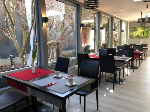 ein Restaurant mit Tischen, Stühlen und Fenstern in der Unterkunft Allgäuhotel Memmingen Nord in Memmingen