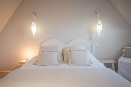 a white bed with white pillows and lights on it at Les Étangs des Couartes in Saint-Josse