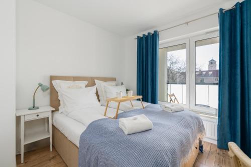 a bedroom with a bed and a window with blue curtains at Rezydencja Rejtana with FREE GARAGE Poznań by Renters in Poznań