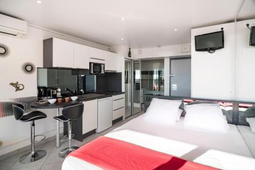 une chambre avec un grand lit blanc et une cuisine dans l'établissement Studio Village Naturiste Spy on me, au Cap d'Agde