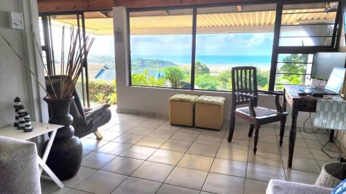 a living room with a table and chairs and windows at Seaview Villa 25 in Shelly Beach