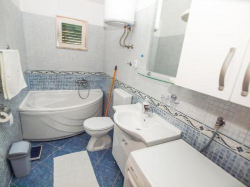 een badkamer met een wastafel, een toilet, een bad en een wastafel bij Apartmani Abesinac in Makarska