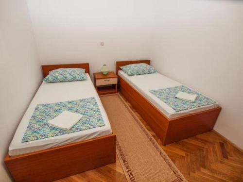 two twin beds in a room with wooden floors at Apartmani Abesinac in Makarska