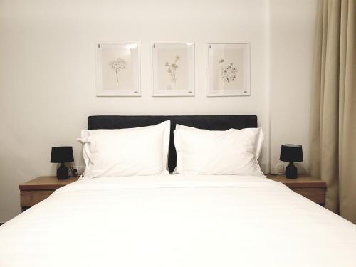 a bedroom with a white bed with three pictures on the wall at Eantos Studios and Suites in Perea