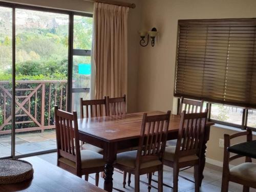 a dining room with a table and chairs and a balcony at Clarens Villas in Clarens