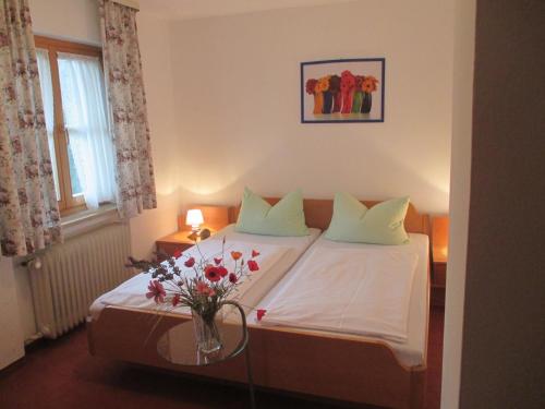 Un dormitorio con una cama con un jarrón de flores. en Ferienhaus Beim Veitele, en Mittenwald