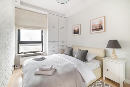 a white bedroom with a bed and a window at Bartycka Elegant Apartment in Warsaw