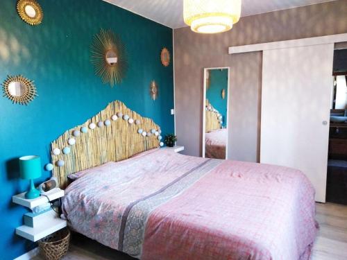 une chambre avec un grand lit et un mur bleu dans l'établissement Le Lou Mazet 1951, à Saint-Nazaire-des-Gardies