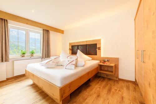Schlafzimmer mit einem Bett mit weißer Bettwäsche und einem Fenster in der Unterkunft Der Kleinwalsertaler Rosenhof in Mittelberg