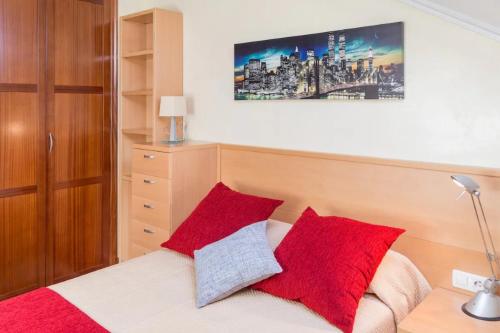 1 dormitorio con 1 cama con almohadas rojas en Vivienda de Uso Turístico CASA DA ROISA, en Santiago de Compostela