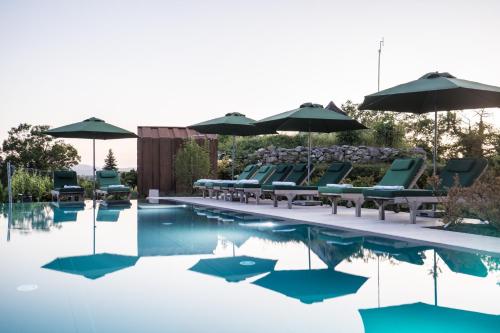 a pool with lounge chairs and umbrellas on the side at Winzarei, Weingut Tement in Berghausen