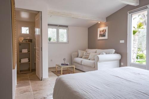 une chambre avec un lit blanc et un canapé dans l'établissement Maison de vacances Villa Cardabella, à Le Tignet