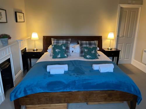 a bedroom with a large bed with blue sheets and pillows at The Richmond Arms Rooms in Funtington