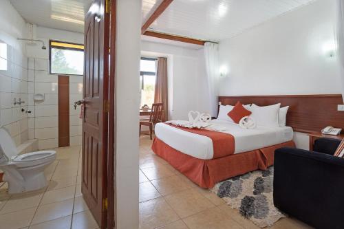 ein Schlafzimmer mit einem Bett und ein Badezimmer mit einer Toilette in der Unterkunft The Kyaka Hotel in Machakos