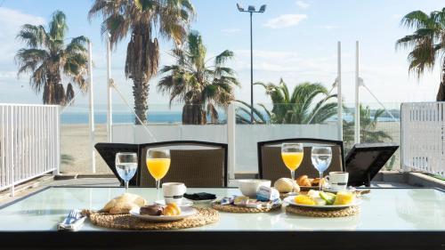 una mesa con comida y bebida en un balcón con vistas a la playa en El Coso en Valencia