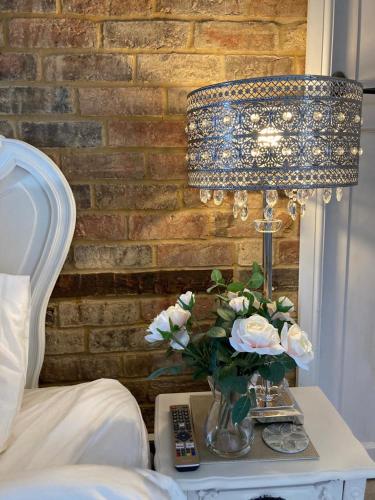 a table with a vase of flowers and a lamp at The Willowford in Milton Keynes
