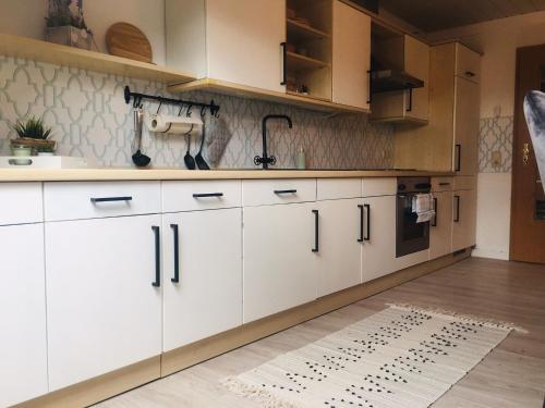 a kitchen with white cabinets and a rug on the floor at Ferienwohnung Brehm in Bad Staffelstein