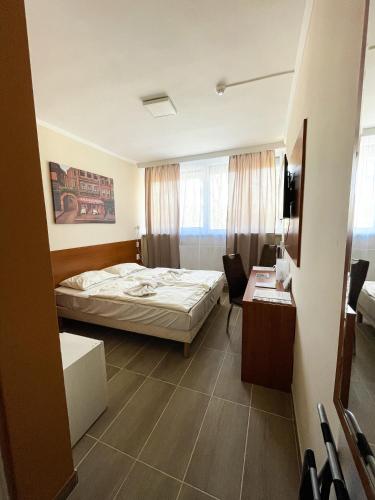 a hotel room with a bed and a desk at Öreg-tó Hotel és Rendezvénytér in Tata