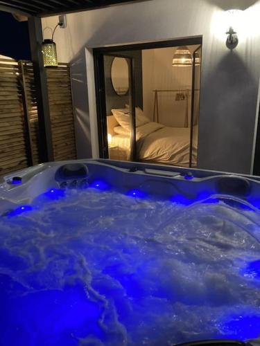 - une baignoire bleue dans une chambre avec un miroir dans l'établissement SPA & SERENITE, aux Portes de Disney et de Paris, à Villiers-sur-Morin