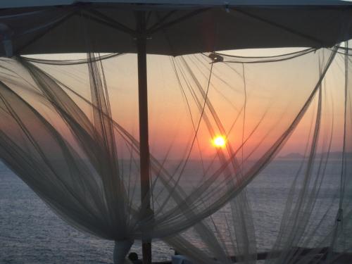 an umbrella on the beach with the sunset in the background at Waterfront villa "Afros" with a pool, direct access to the sea and a small beach in Koundouros
