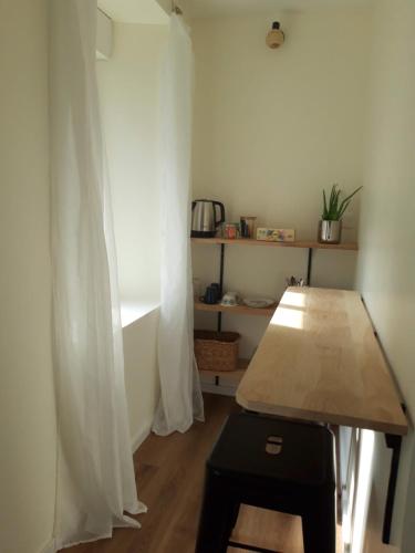 a room with a wooden table and a white curtain at Agréables chambres indépendantes - Coutances centre in Coutances