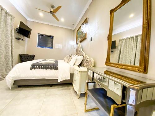 a bedroom with a bed and a mirror at Le Grant Guesthhouse in Kroonstad