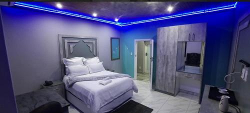 a blue room with a bed and a mirror at National Lodge in Benoni