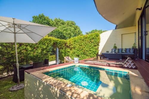 a swimming pool with an umbrella next to a house at Moon Cottage in Choeng Mon Beach