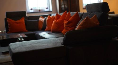 sala de estar con sofá negro y almohadas de color naranja en Wandas Domizil mit Whirlpool en Untermerzbach