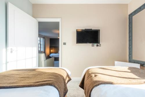 a bedroom with two beds and a tv on the wall at Staunton Arms in Staunton in the Vale