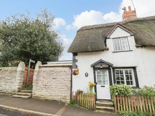 a white cottage with a thatched roof at Apple Tree Cottage in Evesham