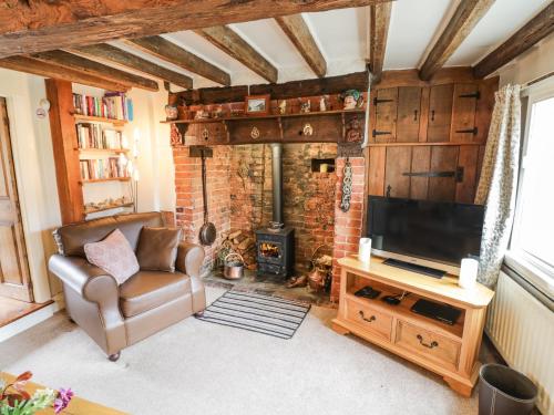 a living room with a couch and a television at Apple Tree Cottage in Evesham