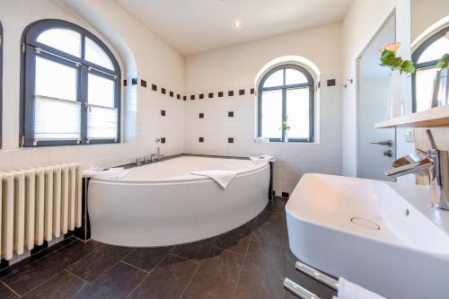 a white bathroom with a tub and a sink at Spitzhaus in Radebeul
