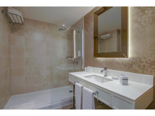 a bathroom with a sink and a mirror and a tub at Limak Cyprus Deluxe Hotel in Iskele